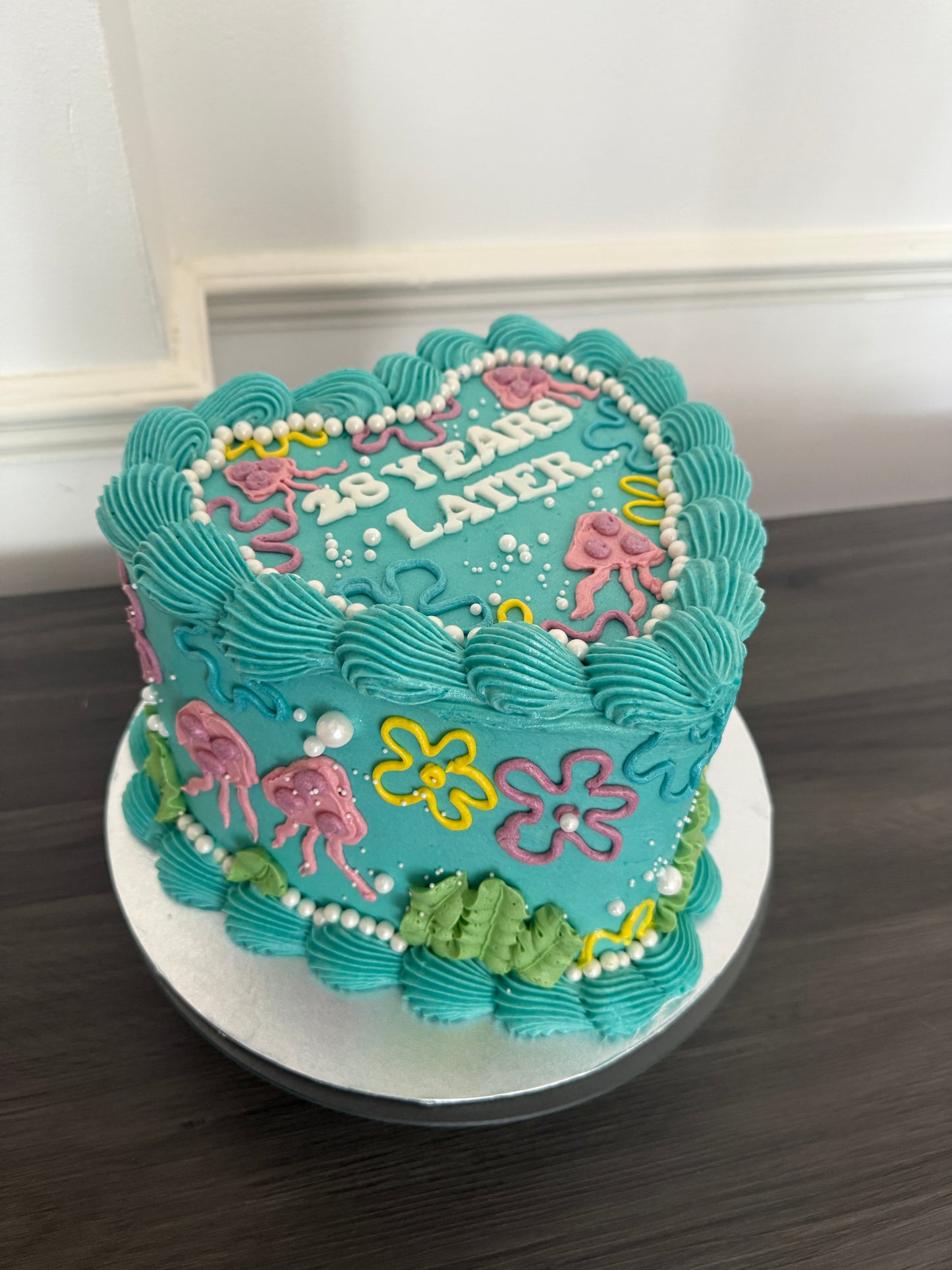 Unique cartoon heart birthday cake with blue icing, pastel piping, and SpongeBob 25 Years Later theme – order for same day and next day delivery in Chigwell, Woodford, and Romford from CakeTrays.co.uk.