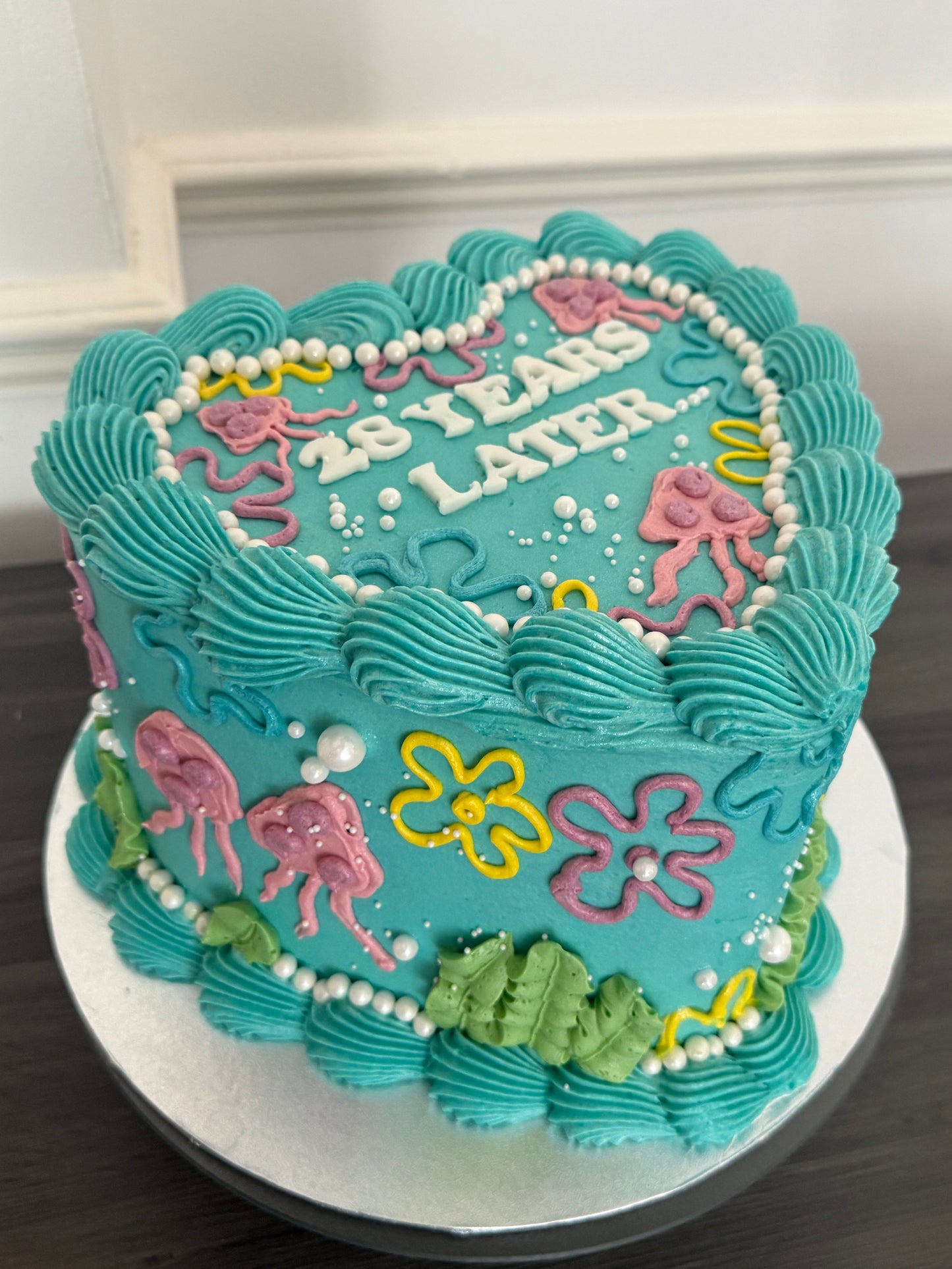 Unique cartoon heart birthday cake with blue icing, pastel piping, and SpongeBob 25 Years Later theme – order for same day and next day delivery in Chigwell, Woodford, and Romford from CakeTrays.co.uk.