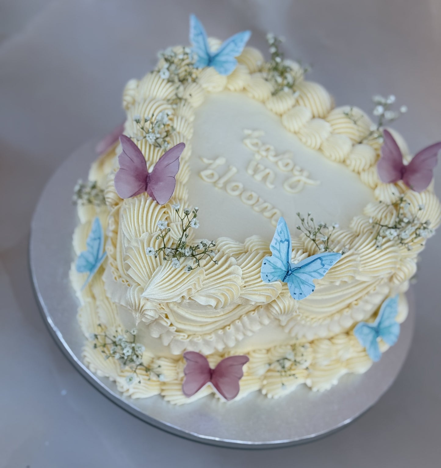 Baby in Bloom Gender Reveal Heart Cake decorated with pastel butterflies and delicate baby’s breath flowers, made for baby showers and gender reveal parties in East London.