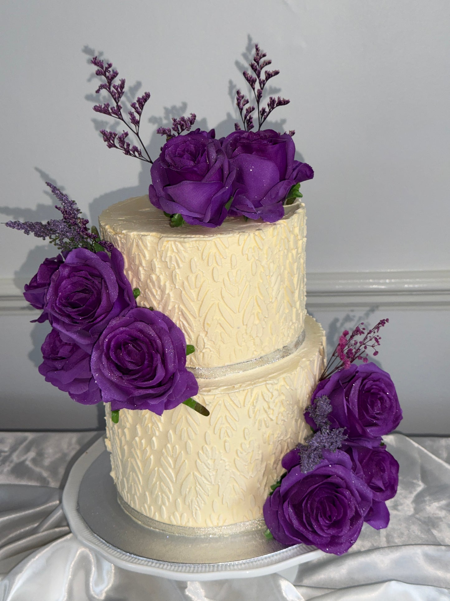 Amethyst Rose Embossed Two-Tier Wedding Cake with ivory buttercream, embossed floral texture and purple rose clusters, delivered by Cake Trays in Romford RM1 and Gidea Park.