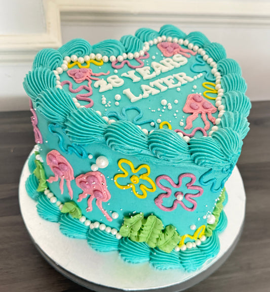 25 Years Later heart-shaped birthday cake with bright blue icing and SpongeBob style decoration – CakeTrays.co.uk same day and next day delivery in Romford, Ilford, and East London.