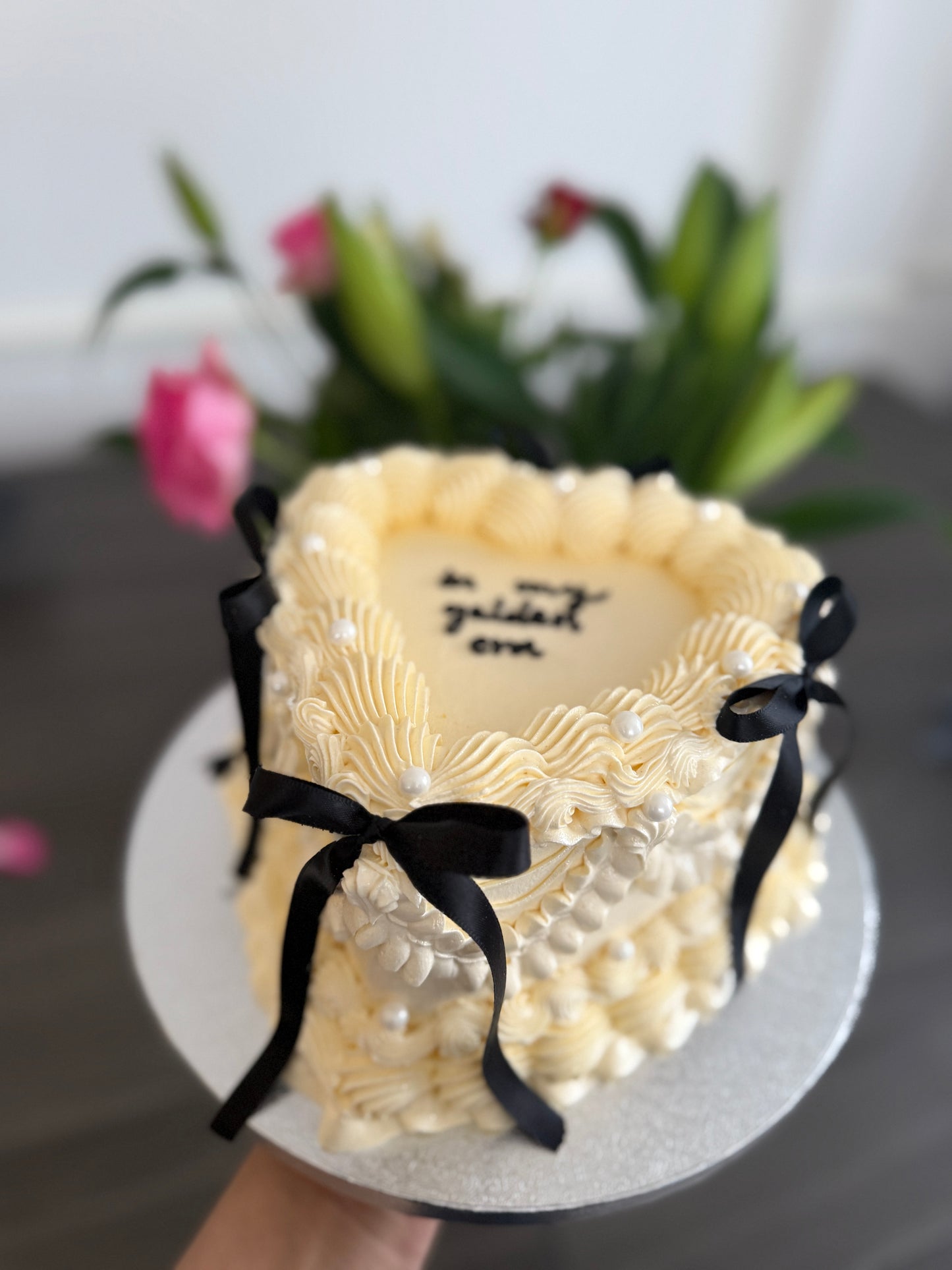 Elegant golden era heart-shaped cake with vintage buttercream swirls, pearls, and black bows – perfect for birthdays and celebrations in Ilford, Barking, and Dagenham.