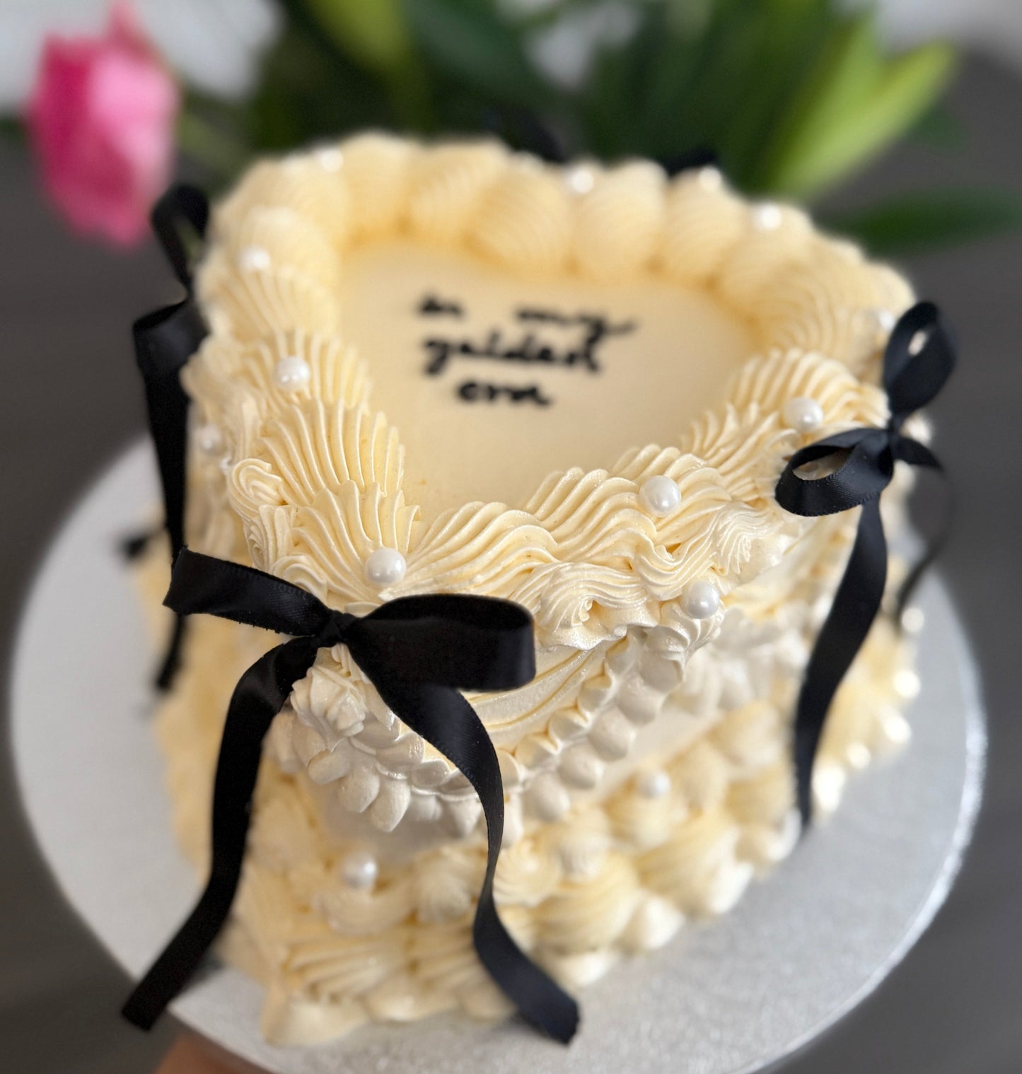 Elegant golden era heart-shaped cake with vintage buttercream swirls, pearls, and black bows – perfect for birthdays and celebrations in Ilford, Barking, and Dagenham.