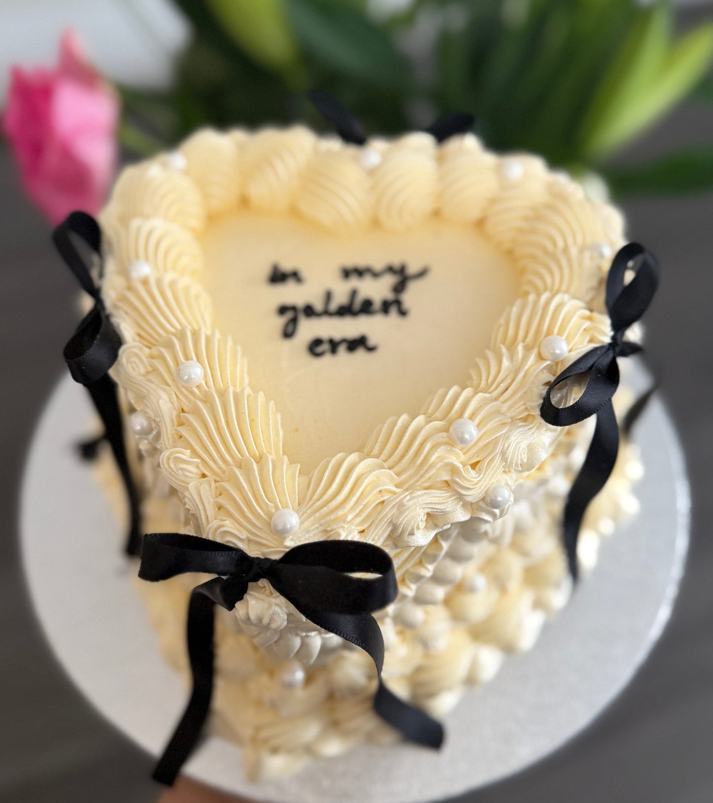 Ivory vintage heart cake with decorative piping, black ribbon bows, and pearl accents – order online from CakeTrays.co.uk for delivery across East Ham, Walthamstow, and Romford.