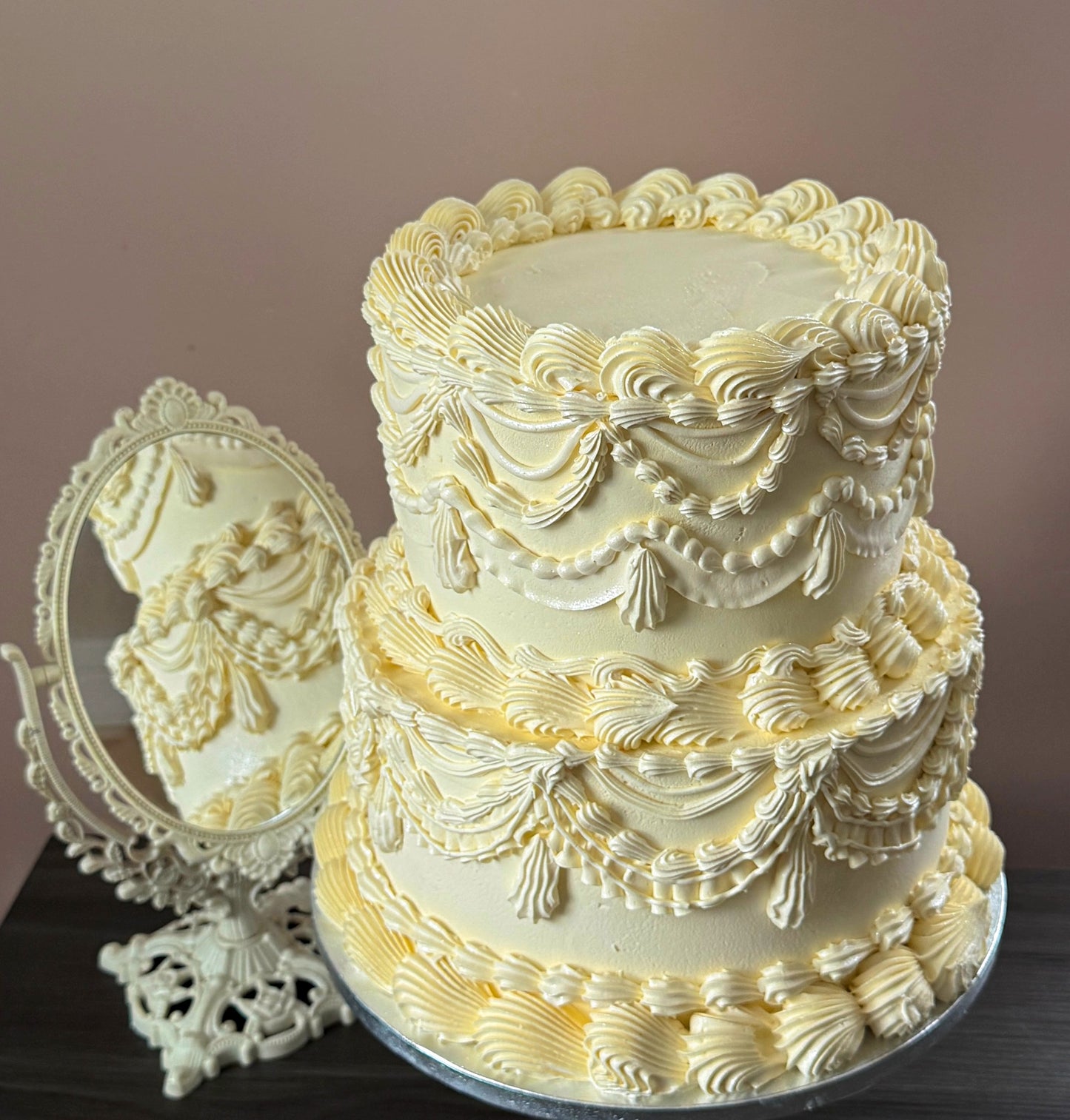 Close view of the ivory vintage Lambeth cake beside an ornate mirror showing the piped drapes and tassels — custom cakes East London, Romford and Ilford.