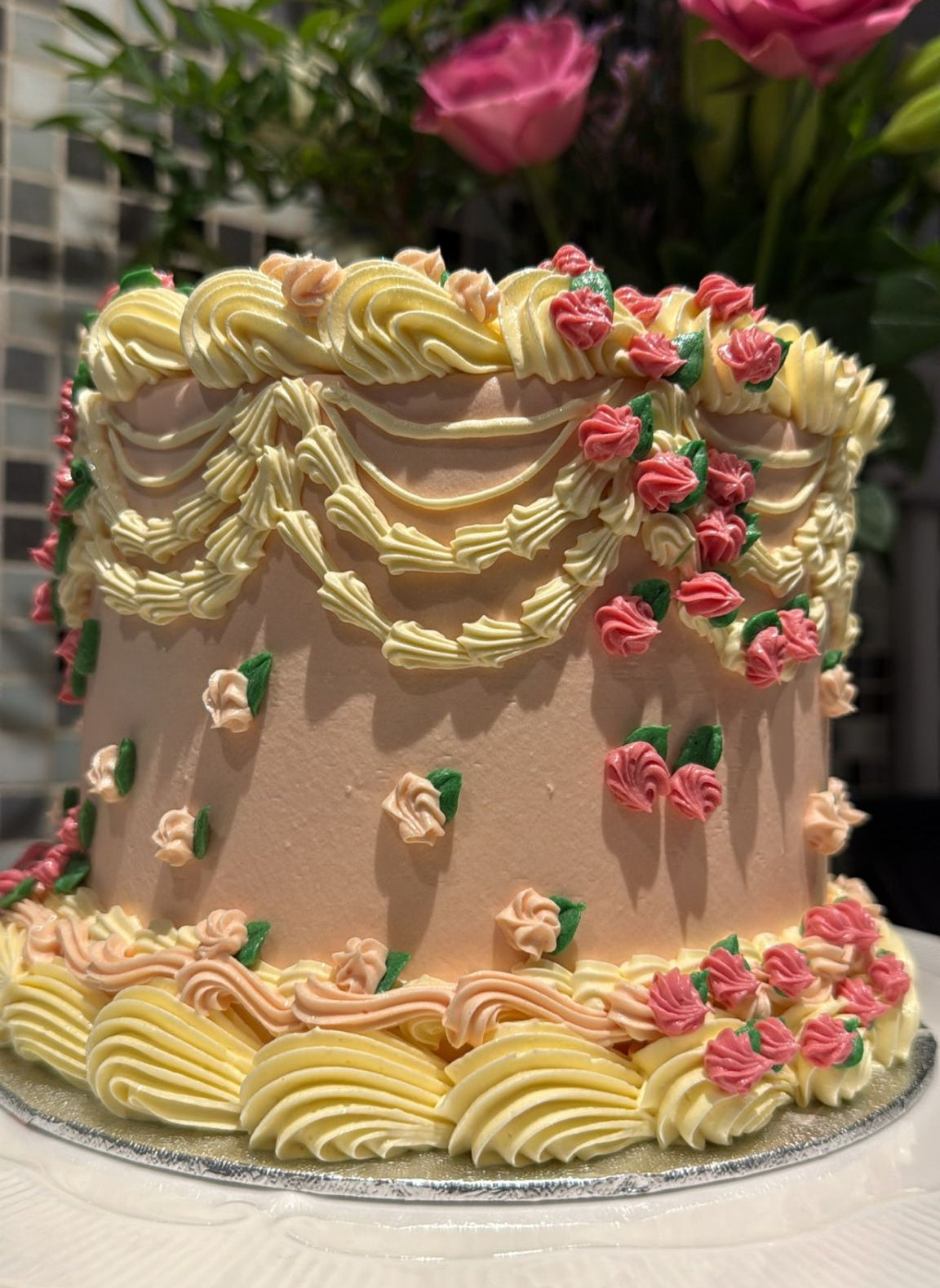 Blush peach vintage Lambeth cake with pale-lemon swags and pink rosebuds — custom cakes East London, Romford and Ilford.