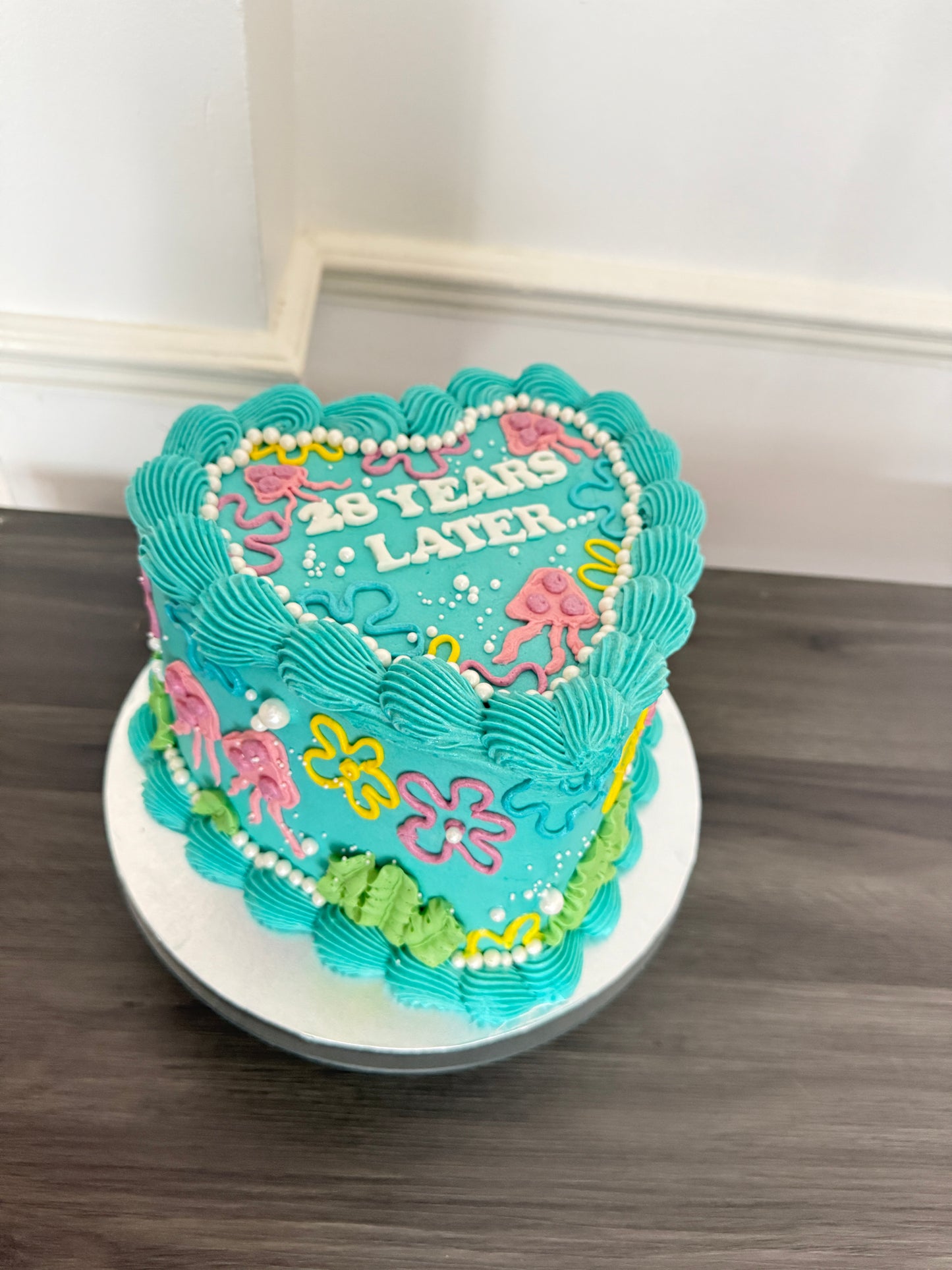 SpongeBob inspired heart birthday cake with turquoise buttercream, floral piping, and ‘25 Years Later’ design – available for same day cake delivery in Romford, Ilford, and East London from CakeTrays.co.uk.