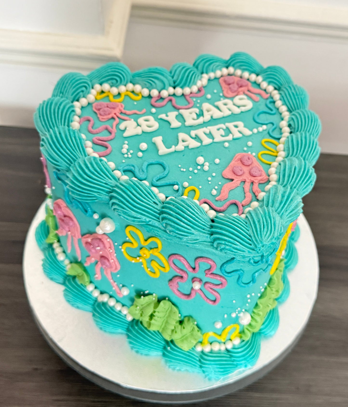 SpongeBob inspired heart birthday cake with turquoise buttercream, floral piping, and ‘25 Years Later’ design – available for same day cake delivery in Romford, Ilford, and East London from CakeTrays.co.uk.