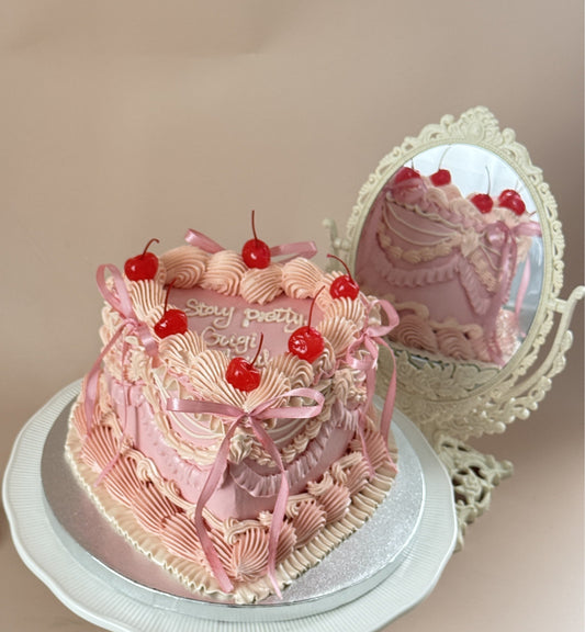 Pink vintage heart cake with piped buttercream frills, red cherries and pink satin bows, an anniversary cake idea for Leytonstone, East London