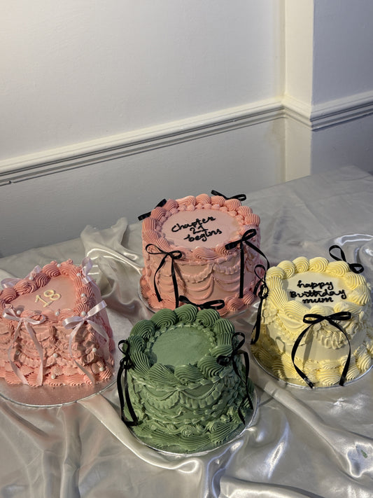 A selection of vintage-style buttercream birthday cakes by Cake Trays delivered in Barking, including a pink 18th, a sage green cake, a Chapter 27 design and a yellow Happy Birthday heart cake with piped ruffles and ribbon bows