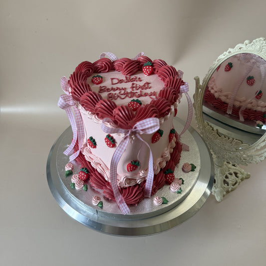 Pink vintage strawberry first birthday cake with gingham ribbon bows and a piped name, a birthday cake for Chigwell IG7 by Cake Trays