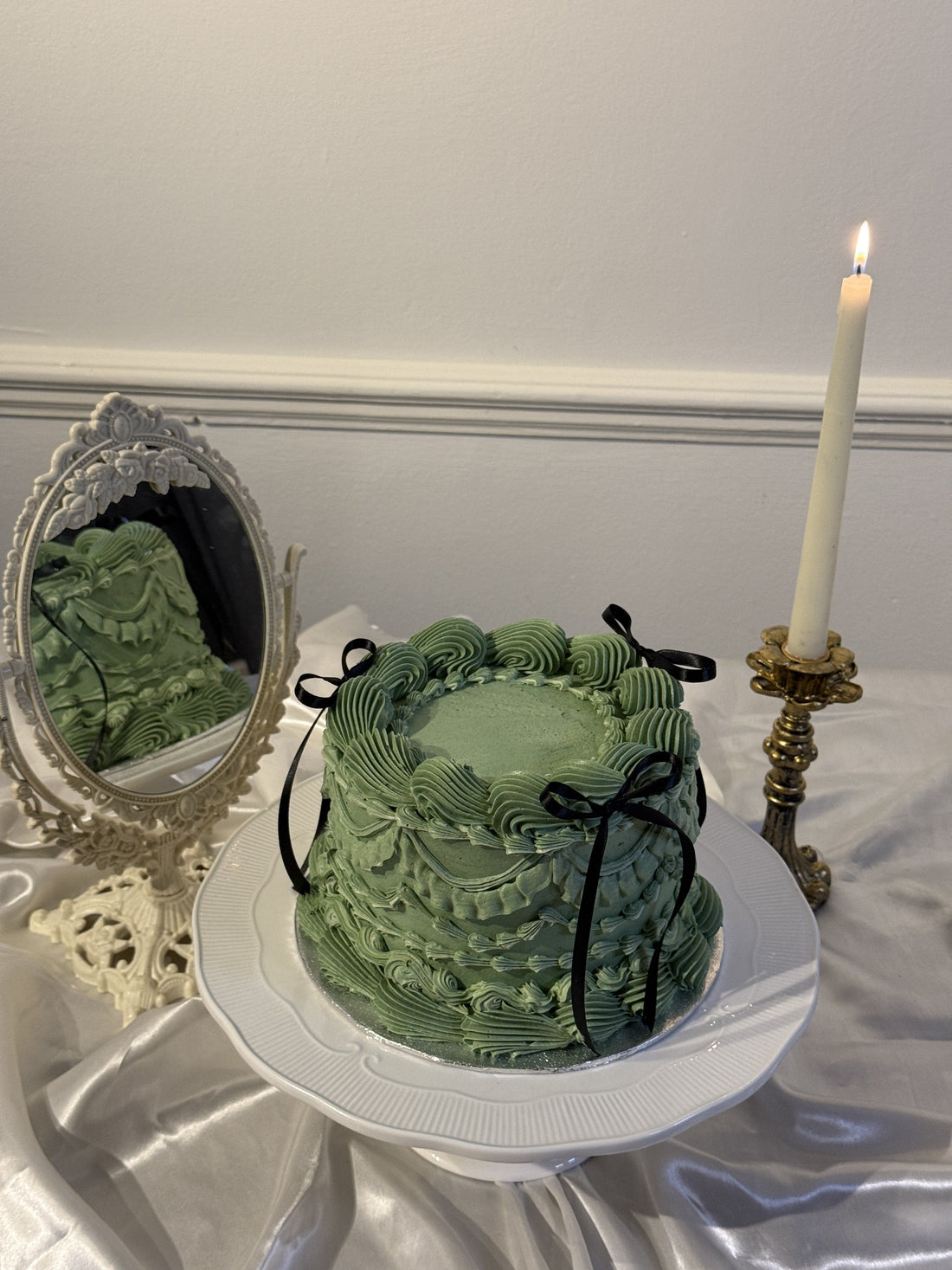 Sage green vintage piped celebration cake with black ribbon bows on a cake stand, made by Cake Trays for delivery in East Ham