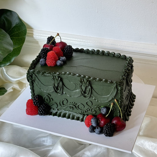 Dark green vintage piped birthday cake topped with fresh raspberries, blackberries, blueberries and cherries, baked by Cake Trays for a milestone birthday in Leyton, East London