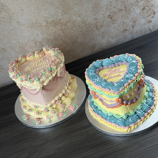 Two pastel vintage buttercream heart cakes piped with Happy Birthday names, baked by Cake Trays for birthday celebrations across East London