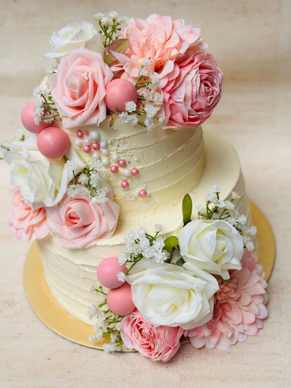 Elegant two-tier floral cake featuring buttercream textures and fresh roses for events in East Ham.