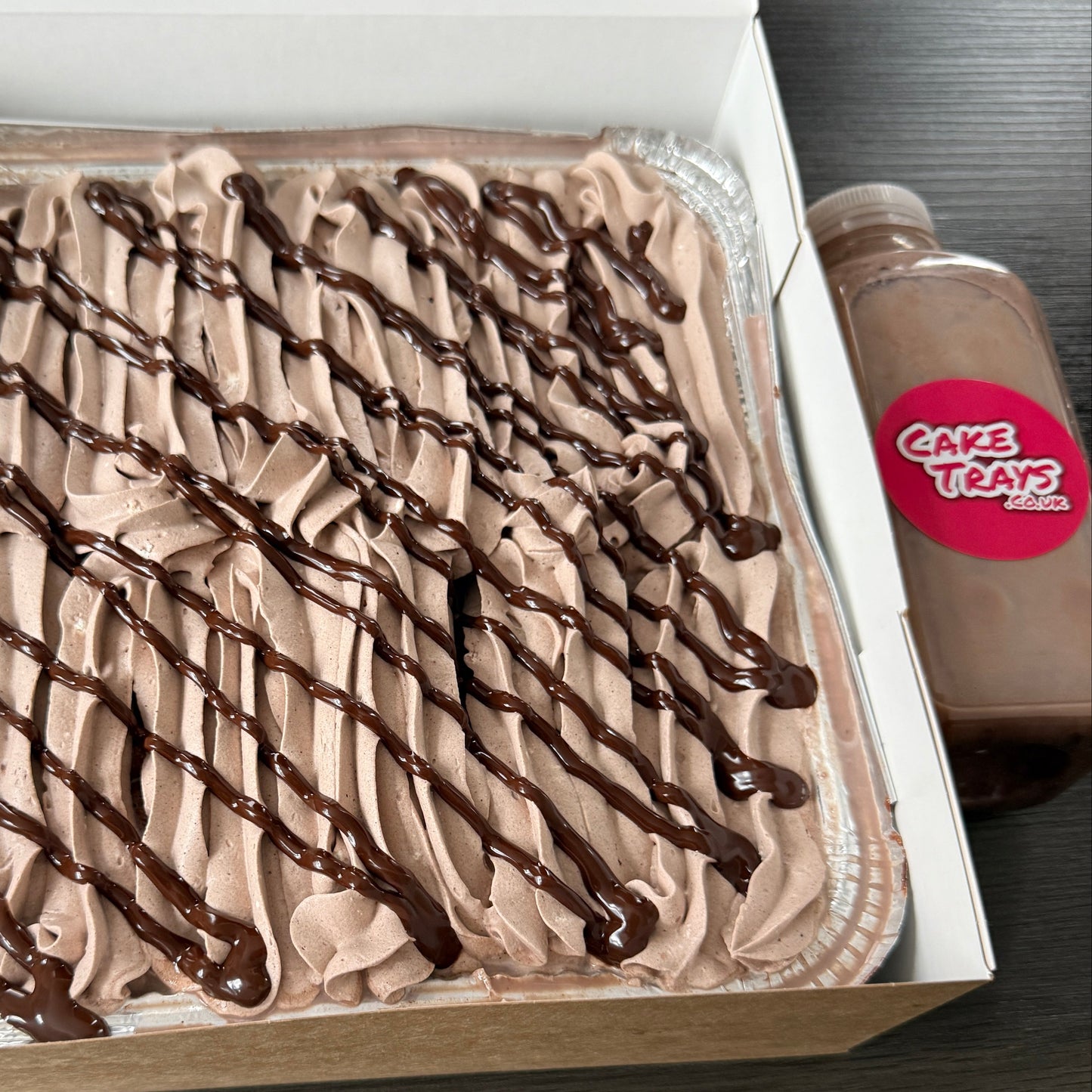 Close up of a rich chocolate tres leches milk cake tray with thick chocolate frosting ripples, serving Ilford and surrounding Essex areas.
