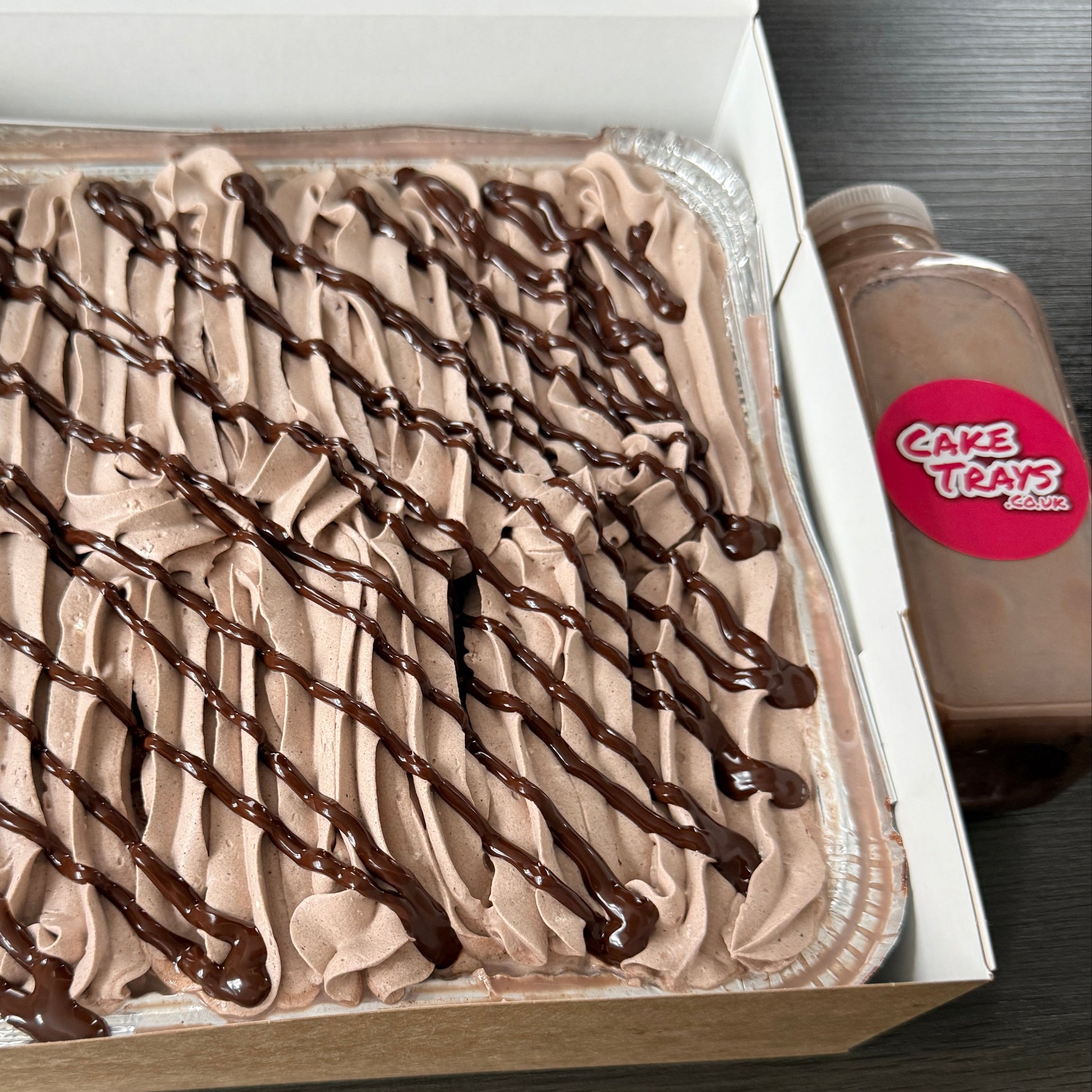 Close up of a rich chocolate tres leches milk cake tray with thick chocolate frosting ripples, serving Ilford and surrounding Essex areas.