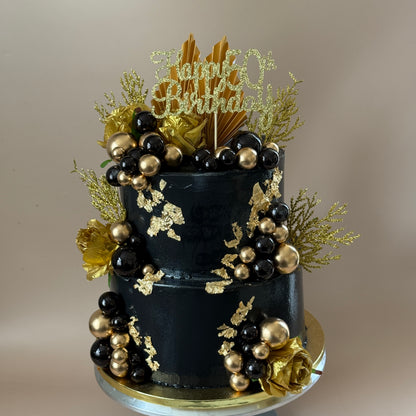 Side view of the black and gold two-tier 50th birthday cake with gold roses and palm fans — custom cakes East London, Romford and Ilford.