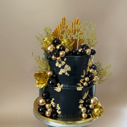 Close detail of gold leaf and black and gold sugar pearls on the two-tier 50th birthday cake — custom cakes East London, Romford and Ilford.