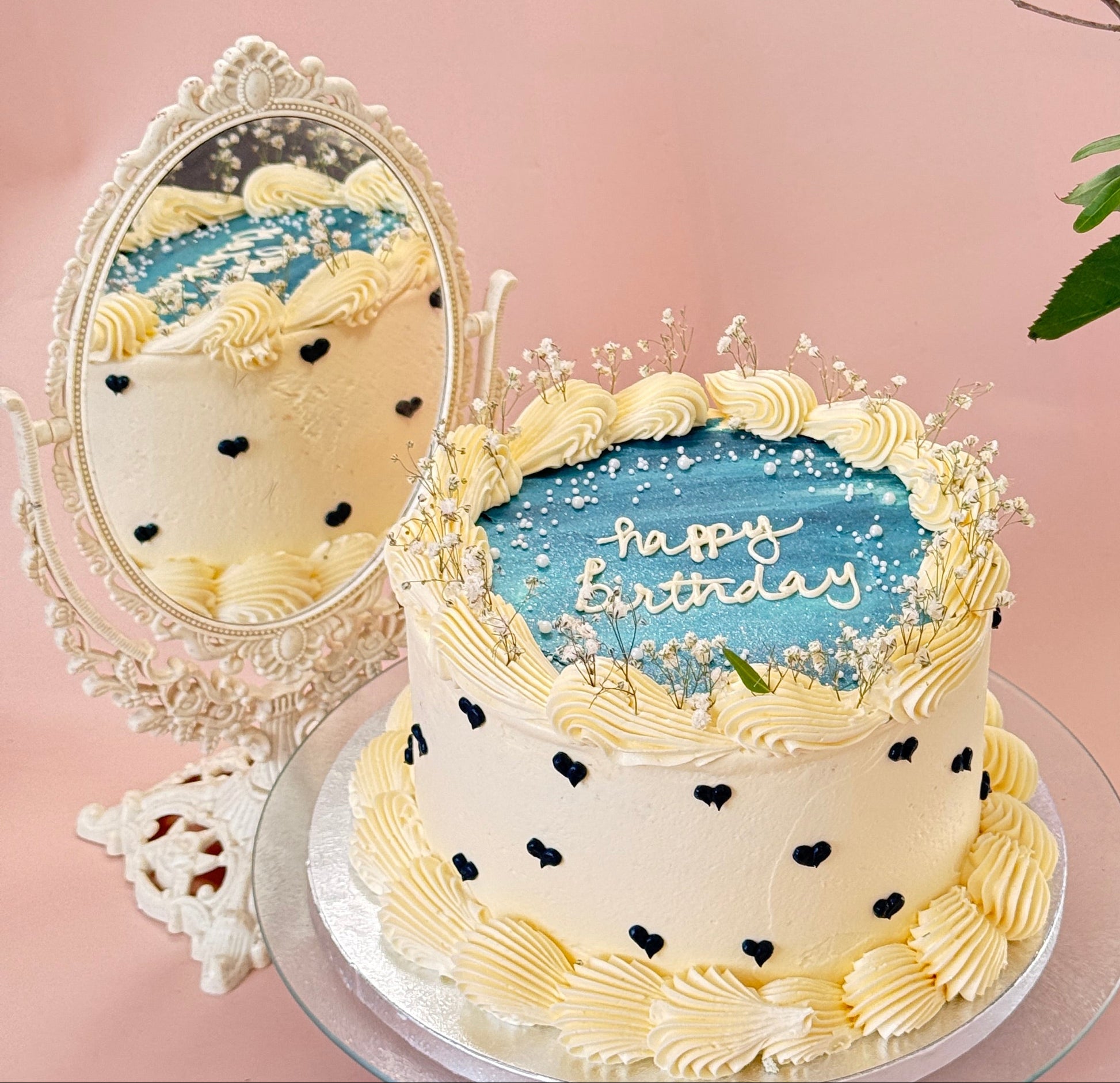 Cream buttercream cake with a blue painted plaque, happy birthday message, piped black hearts and gypsophila — custom cakes East London, Romford and Ilford.