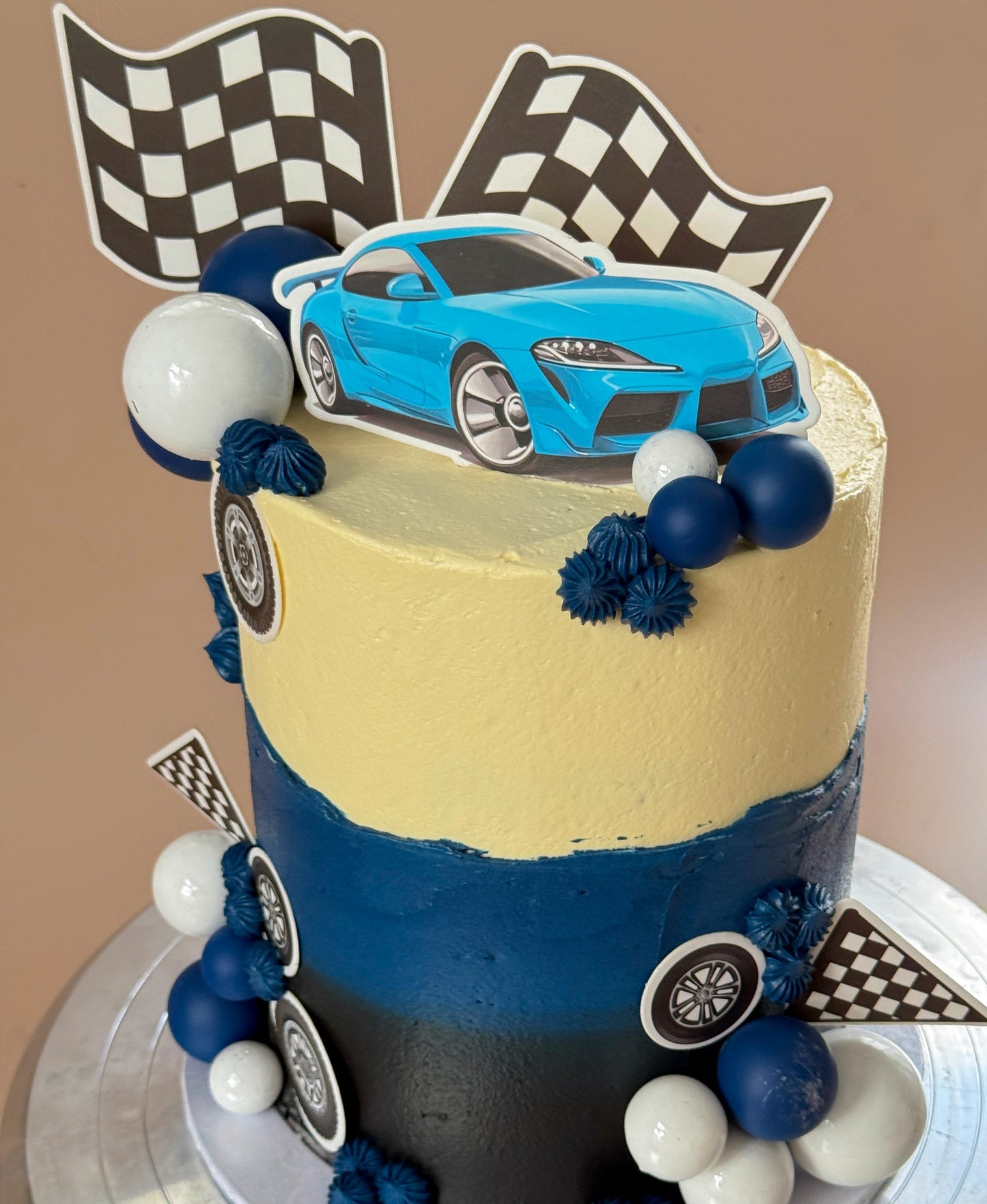 Close up of race car topper and checkered flags on birthday cake, custom cakes East London, Romford and Ilford.