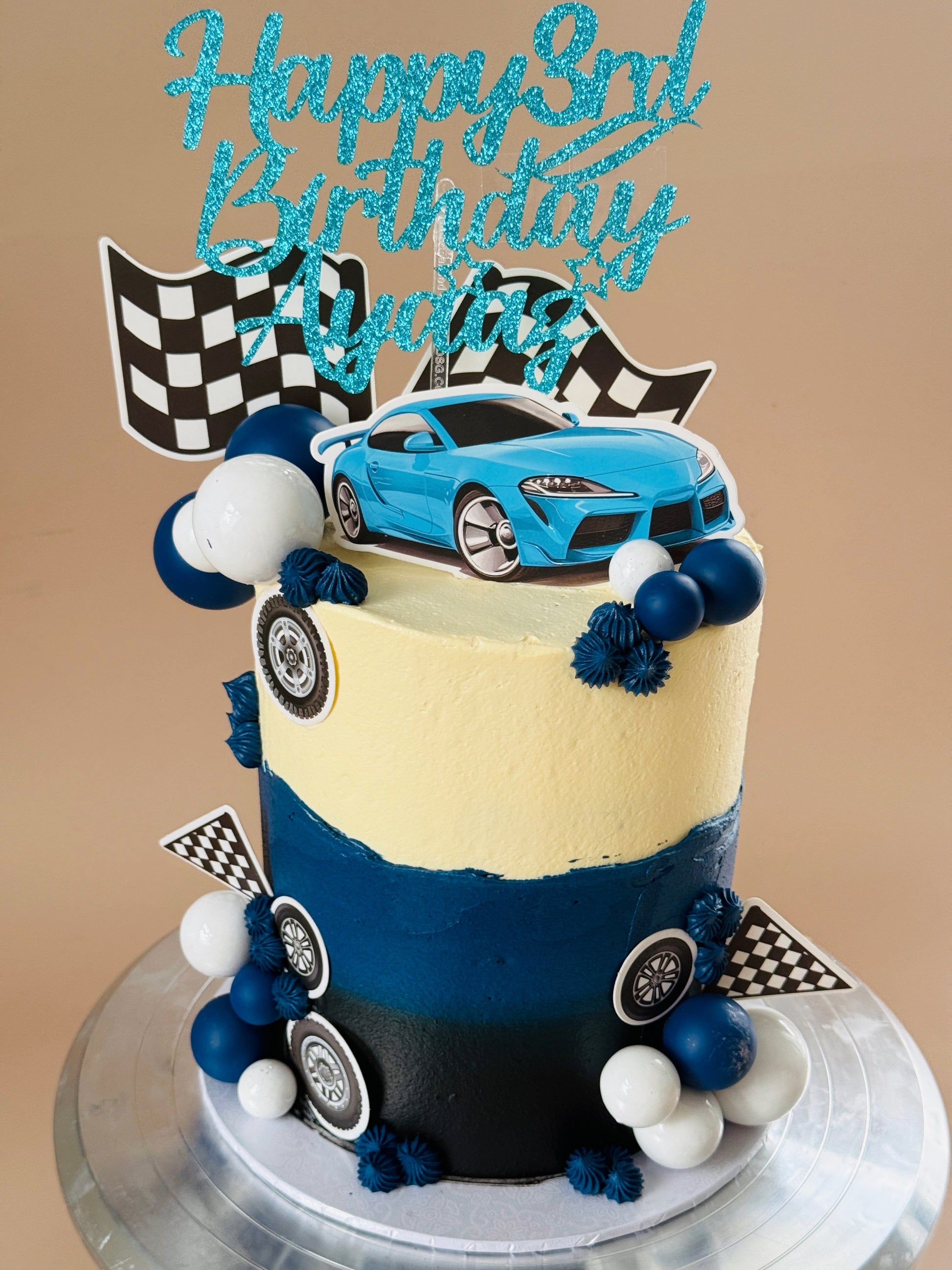 Blue and black race car birthday cake with checkered flags and tyre detailing, custom cakes East London, Romford and Ilford.