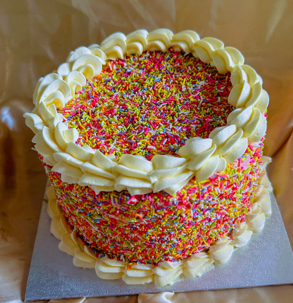 Buy sprinkle birthday cake in Romford and Ilford, colourful sponge covered in rainbow sprinkles with buttercream piping.