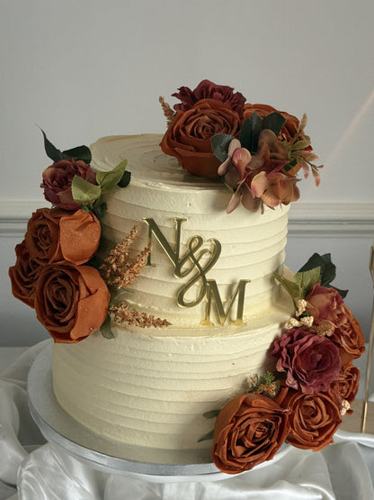 Rust Rose Monogram Wedding Cake with ivory buttercream ridges, gold initials topper and rust orange roses, made by Cake Trays for East London delivery.