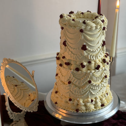 Close-up of the top tier showing vintage Lambeth piping, scalloped swags and burgundy piped roses on an ivory buttercream wedding cake, delivered across Barking IG11 and Dagenham RM8.