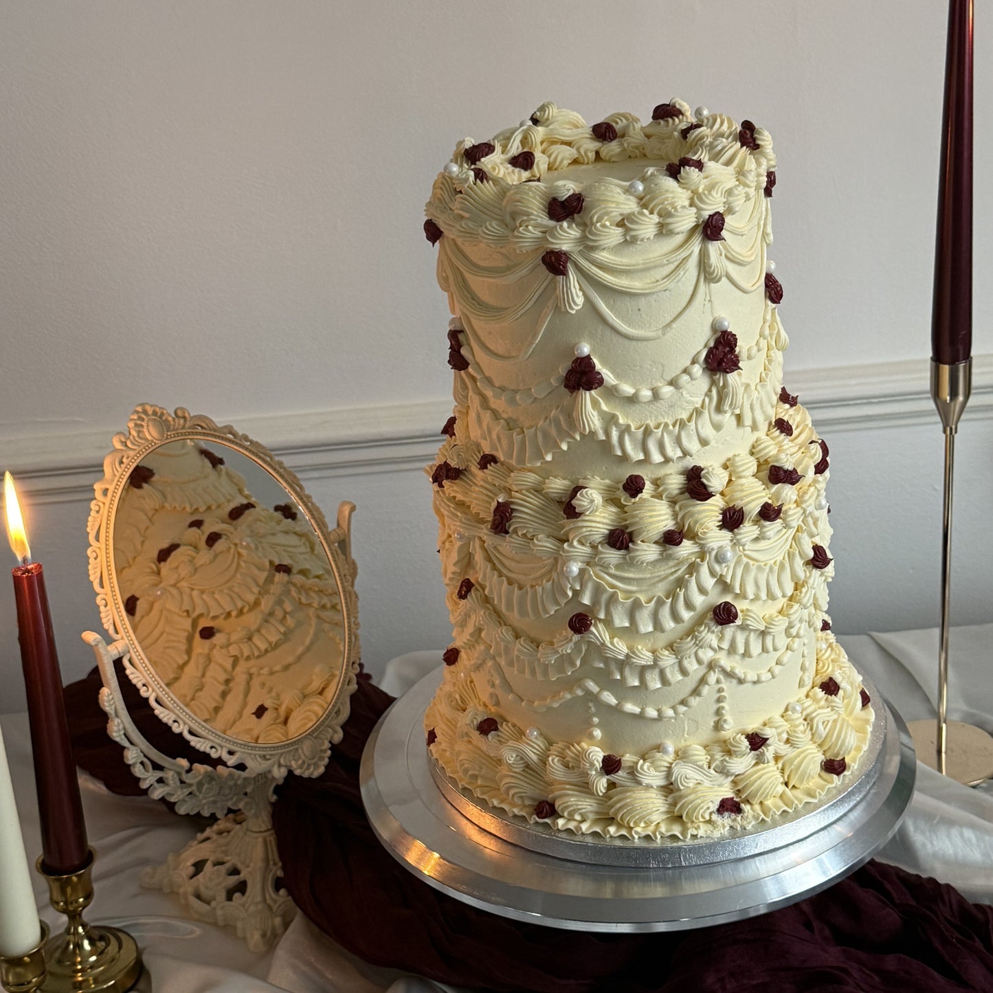 Styled Vintage Burgundy Pearl Lambeth Two-Tier Wedding Cake on a stand with candle styling, perfect for weddings and nikkahs in Stratford E15 and East Ham E6.