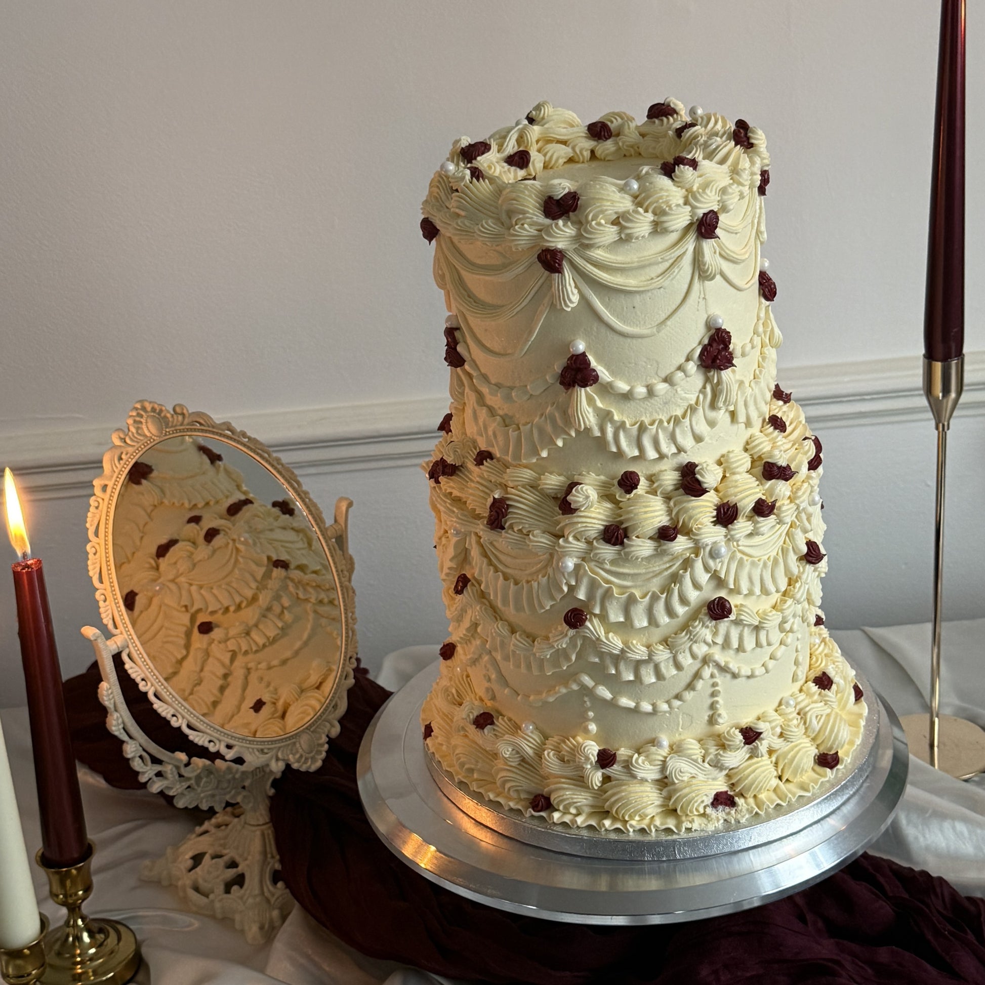 Styled Vintage Burgundy Pearl Lambeth Two-Tier Wedding Cake on a stand with candle styling, perfect for weddings and nikkahs in Stratford E15 and East Ham E6.