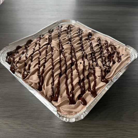 A square foil tray of chocolate milk cake with piped chocolate cream and a dark chocolate drizzle, available for delivery in Romford.