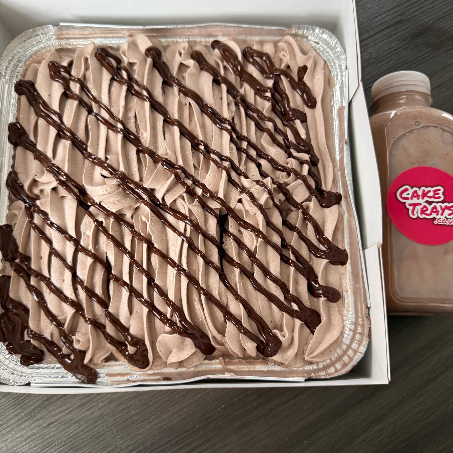 A family sized tray of chocolate milk cake with elegant cream piping, perfect for parties and celebrations in East Ham.
