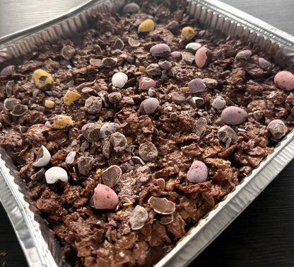 A close up slice of the chocolate crunch cake showing the soft milk soaked sponge rich chocolate ganache and crispy cornflake layers available in Romford.