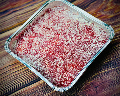 Overhead view of classic jam and coconut school tray bake in a square tin, delivered to Dagenham and Barking.