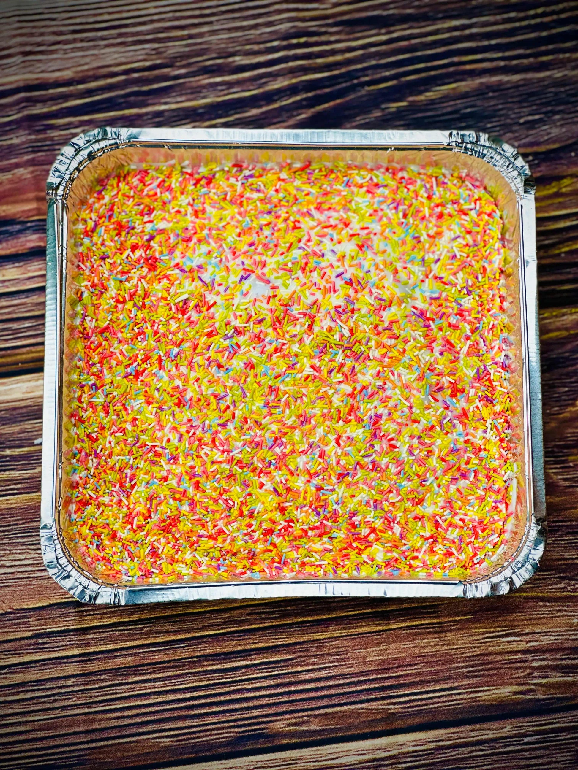 Overhead view of classic school cake baked in a square tin, topped with pink icing and sprinkles, available for delivery in Dagenham and Barking.