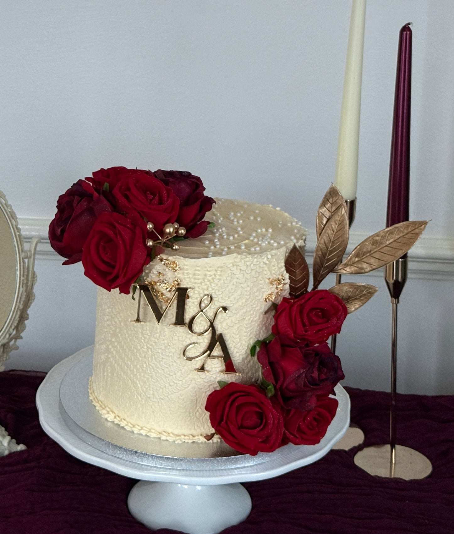 Single tier buttercream wedding cake with personalised gold initials monogram and cascading red rose arrangement from Cake Trays Dagenham