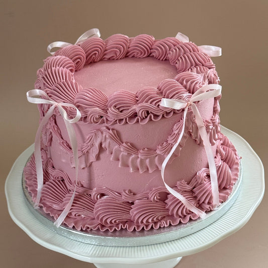 Dusky pink vintage Lambeth cake with hand-piped swags and shells and white satin ribbon bows — custom cakes East London, Romford and Ilford.