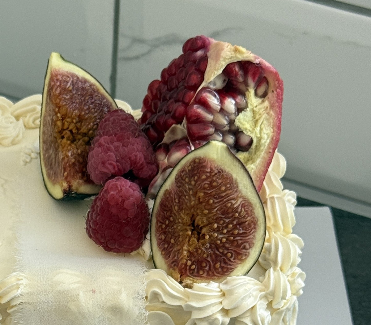 Close up of fresh figs, raspberries and split pomegranate on the sheet cake, custom cakes East London, Romford and Ilford.