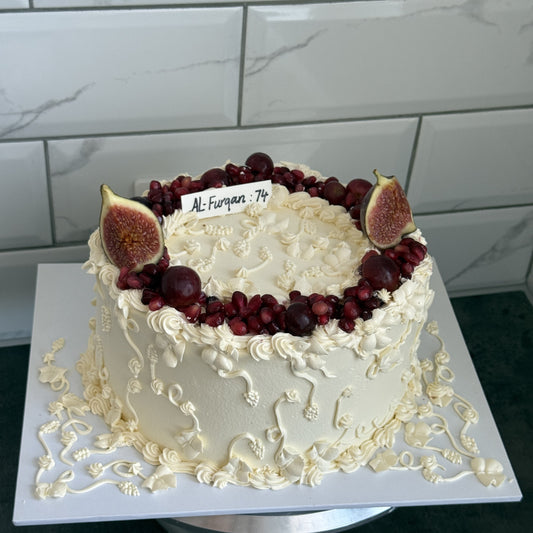 Round ivory Nikkah cake crowned with pomegranate seeds and fresh figs with an Al-Furqan 74 verse card, custom cakes East London, Romford and Ilford.