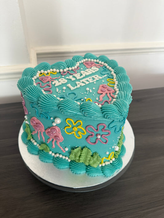 Custom cartoon themed heart cake decorated with colourful flowers, pearls, and ocean-style details – perfect for birthdays with delivery in Barking, East Ham, and East London.