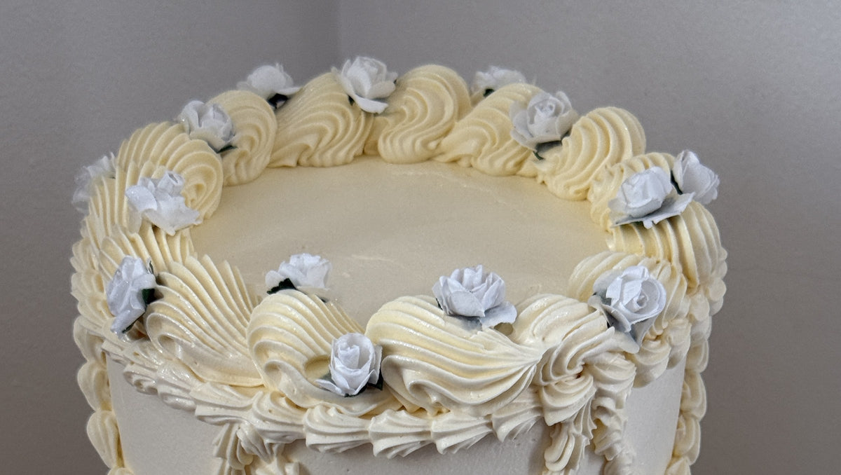 Close up of the top tier shell border and dusty blue roses, custom cakes East London, Romford and Ilford.