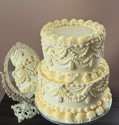 Close view of the ivory vintage Lambeth cake beside an ornate mirror showing the piped drapes and tassels — custom cakes East London, Romford and Ilford.