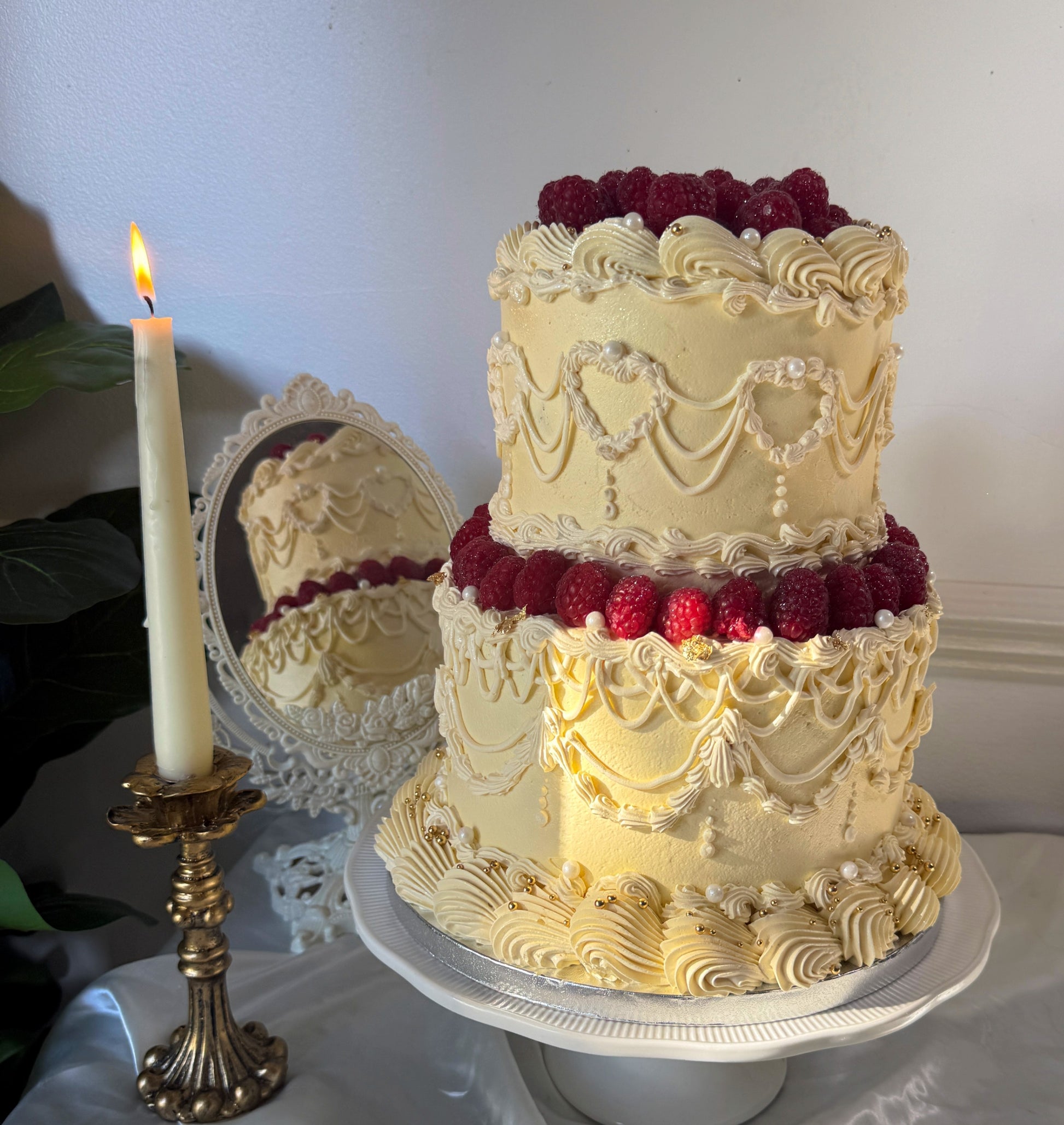 Lemon vintage Lambeth raspberry cake lit by candlelight beside an ornate mirror — custom cakes East London, Romford and Ilford.