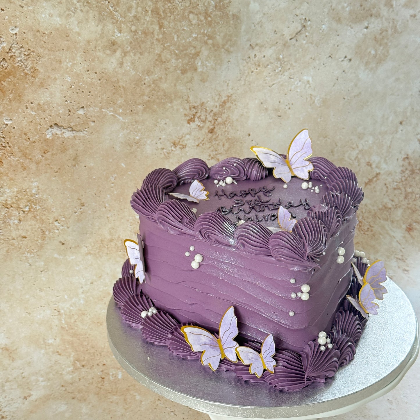 Angled view of the lilac butterfly heart birthday cake with pearls and shell piping — custom cakes East London, Romford and Ilford.