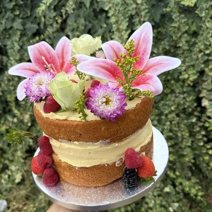 Angled view of the naked sponge cake with lilies and fresh berries, custom cakes East London, Romford and Ilford.