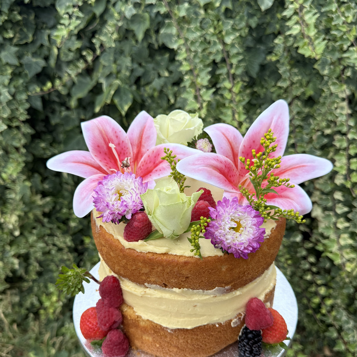 Naked celebration cake with pink lilies, fresh flowers and berries, custom cakes East London, Romford and Ilford.
