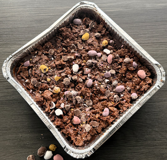Close up detail of the signature chocolate cornflake crunch layer and whole mini eggs on our popular cake tray delivered to Ilford.
