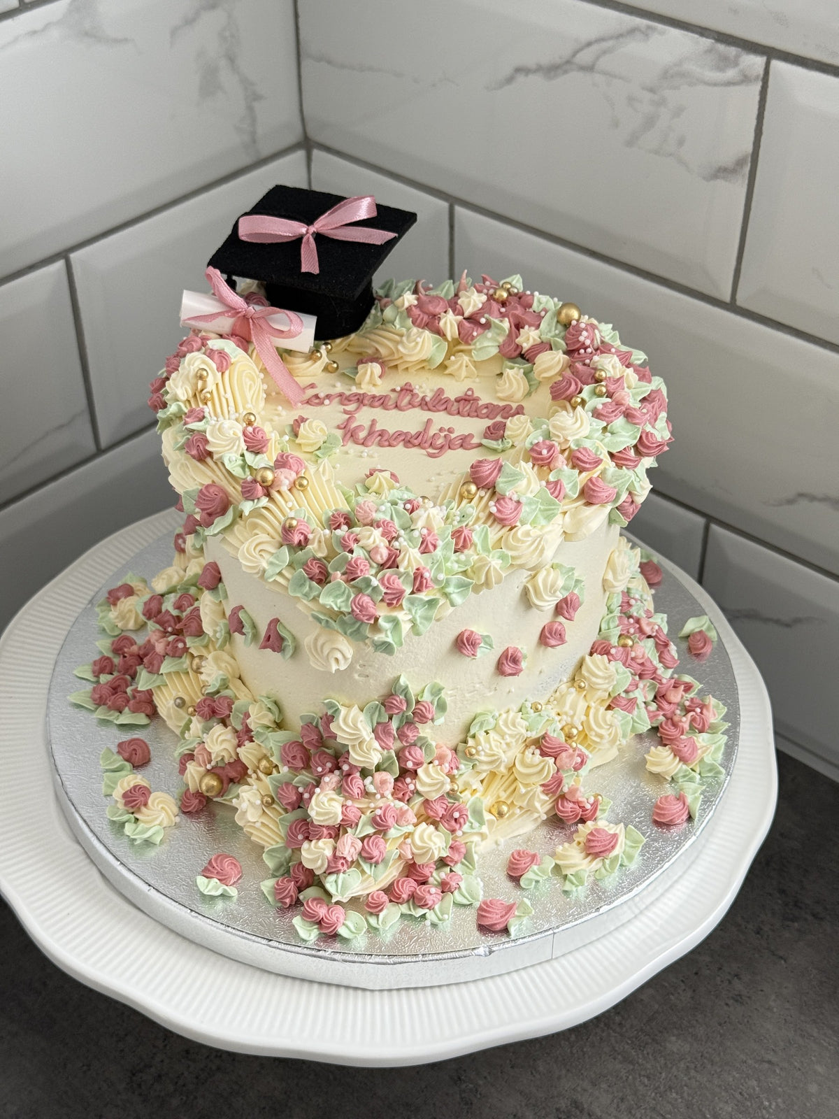 Pastel rosette graduation heart cake with black mortarboard topper and piped congratulations message, custom cakes East London, Romford and Ilford.