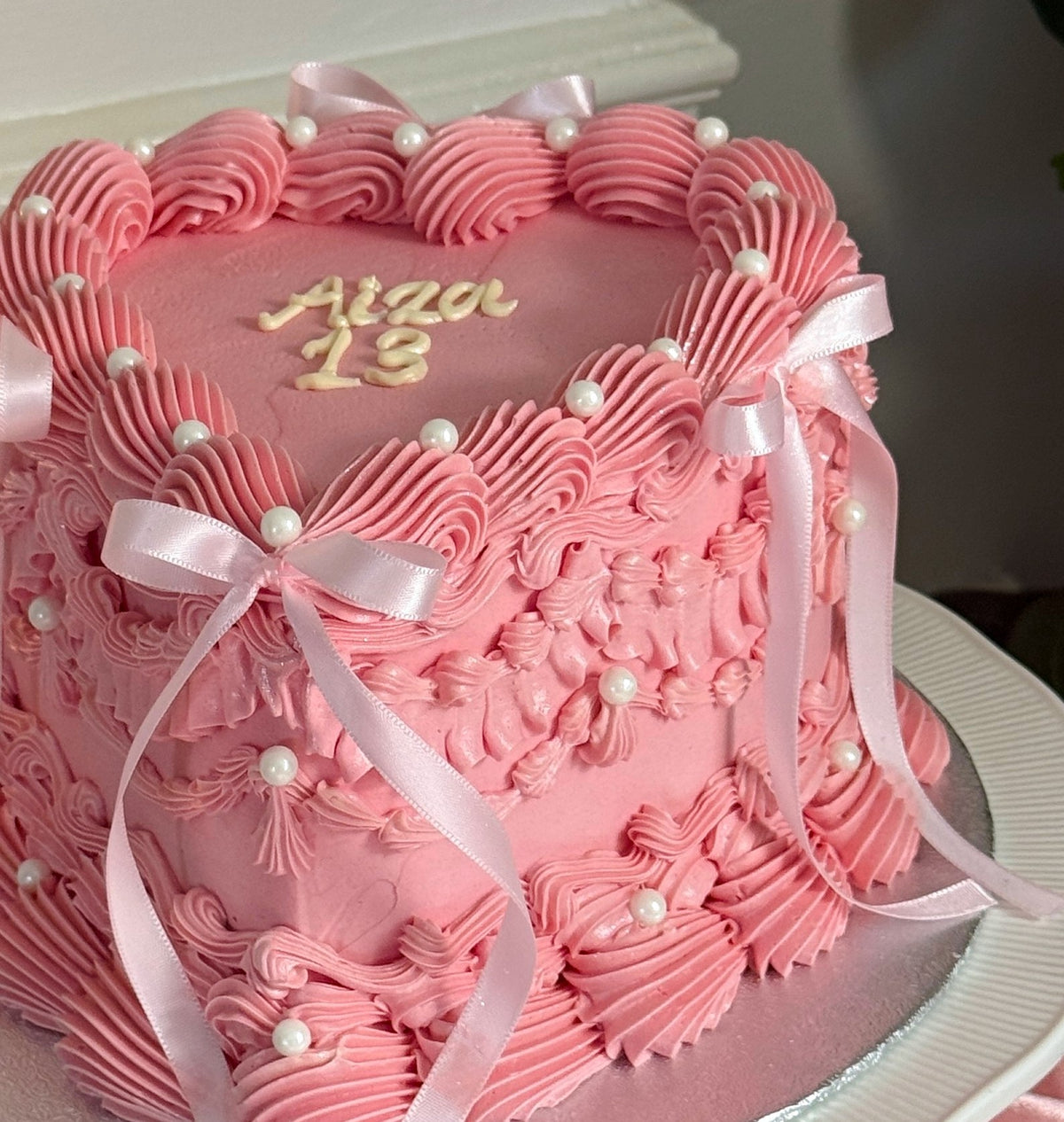 Close up of satin bows and pearls on pink heart cake, custom cakes East London, Romford and Ilford.